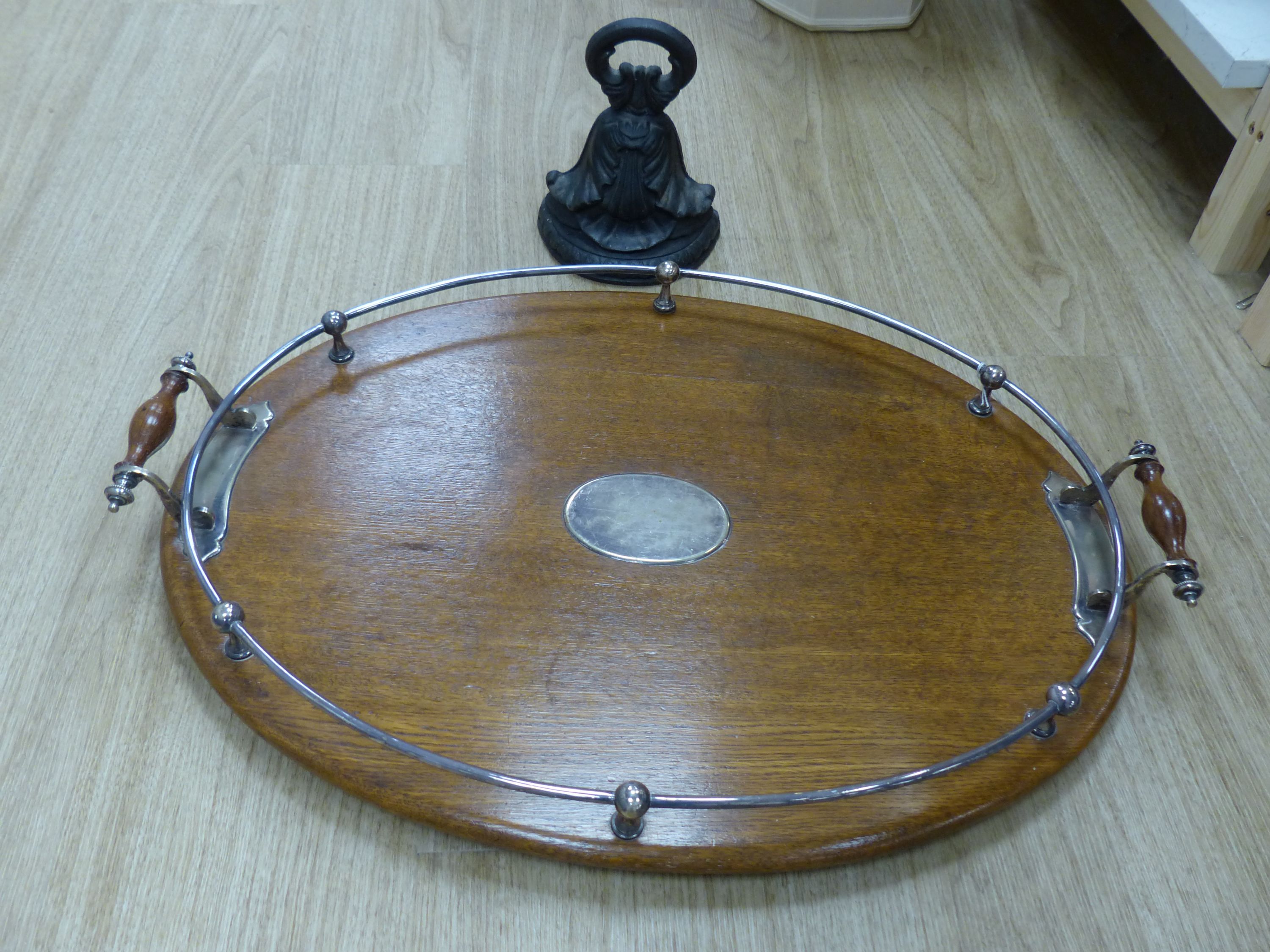 A two handled mahogany oval tray with plated gallery and cartouche and a cast iron door stop